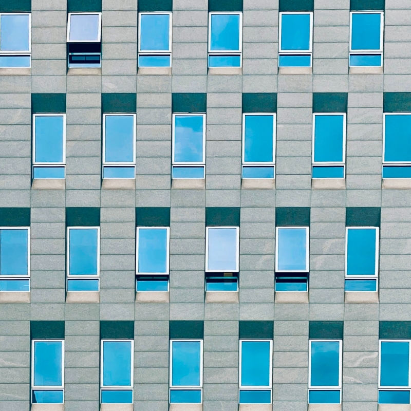 Panther Professional 2 Fassade eines modernen Gebäudes mit regelmäßig angeordneten rechteckigen Fenstern und blauer Spiegelverglasung.