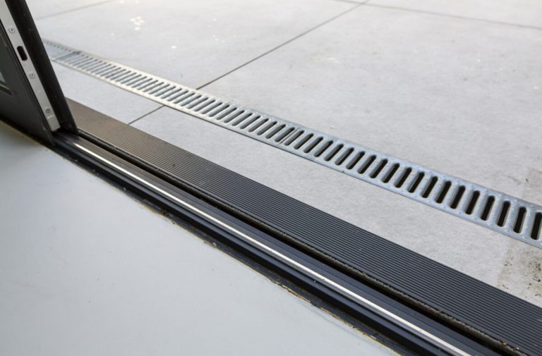 Ariane 2 Bodentiefe Türschwelle mit flacher Führungsschiene und Entwässerungsrinne im Außenbereich.