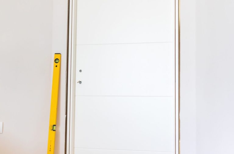 Einbau einer modernen weißen Tür – präzise Ausrichtung im Innenraum Weiße Tür im Innenbereich wird eingebaut, daneben steht eine gelbe Wasserwaage zur Ausrichtung.