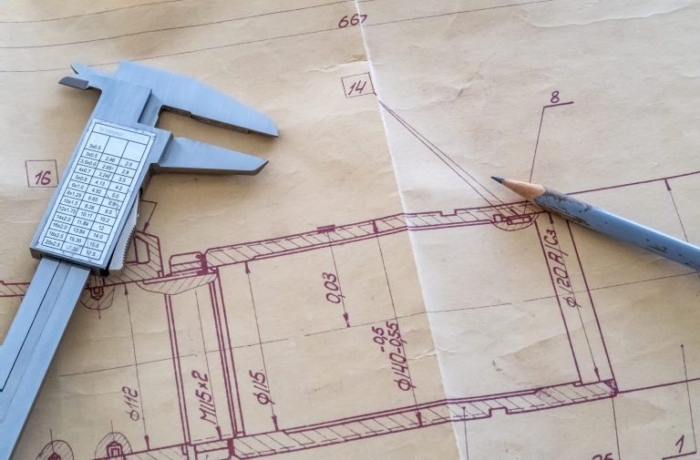 Präzision in der Konstruktion – technische Zeichnung mit Messwerkzeug Technische Zeichnung mit Maßangaben, darauf liegen ein Messschieber und ein gespitzter Bleistift.